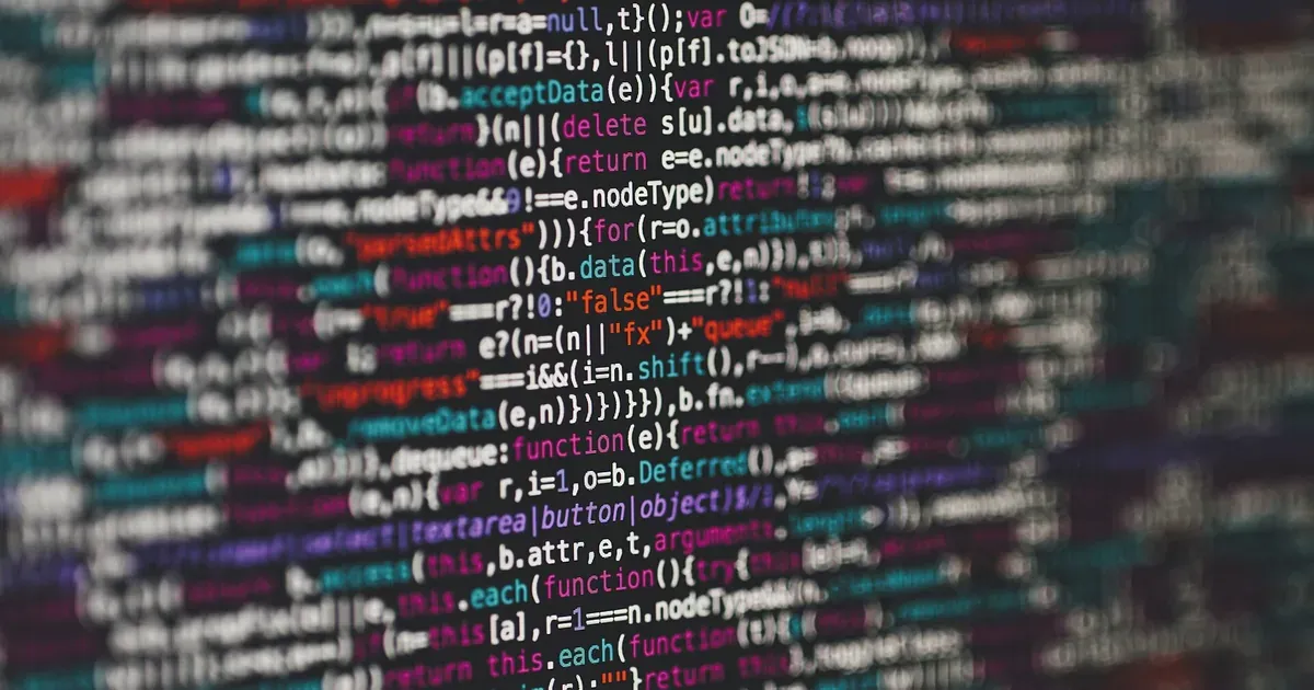 Close-up of colourful source code on a dark screen, partly out of focus